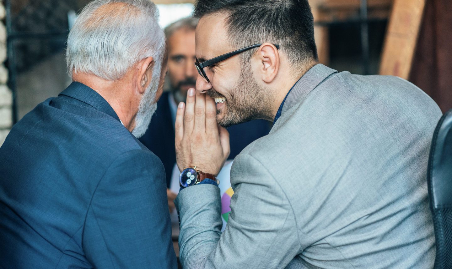 Man whispering into another man's ear