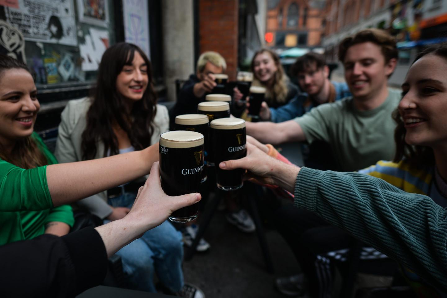 People enjoy drinking Guinness outside a pub in Dublin city center.