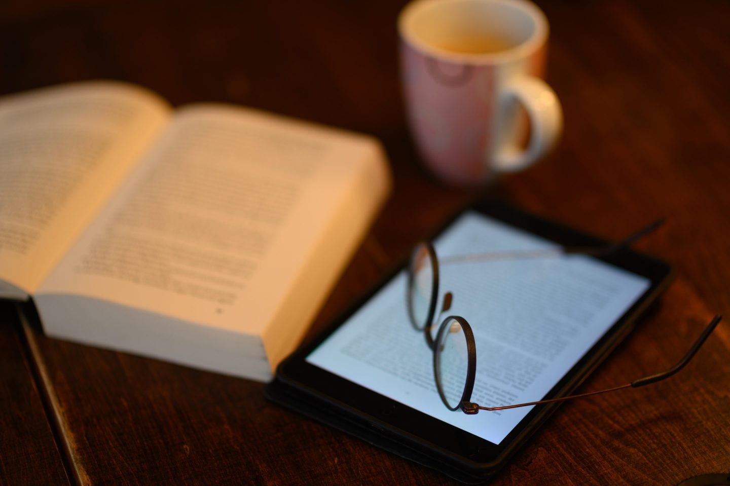 A book and an iPad tablet with an open eBook lying on a table