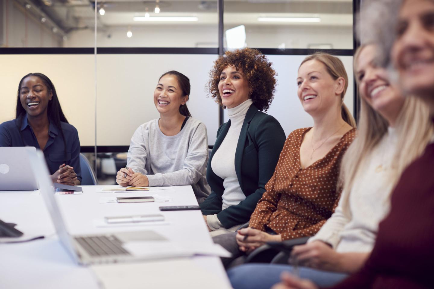 Women conversing at a conference table.