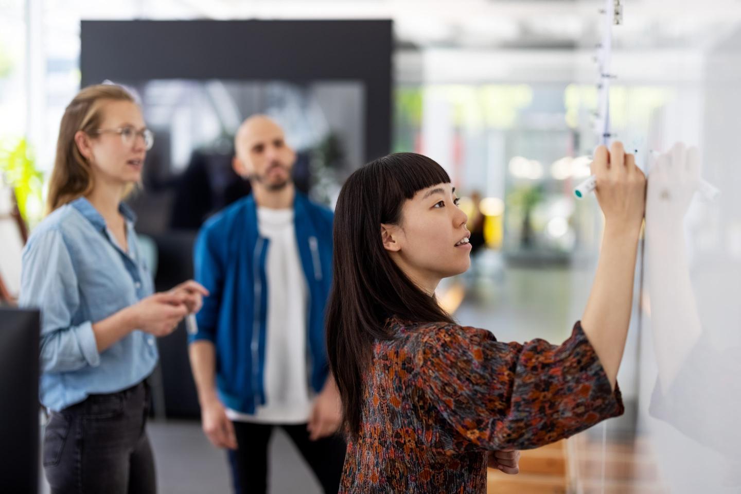 Business woman teaches lesson to colleagues on a whiteboard.