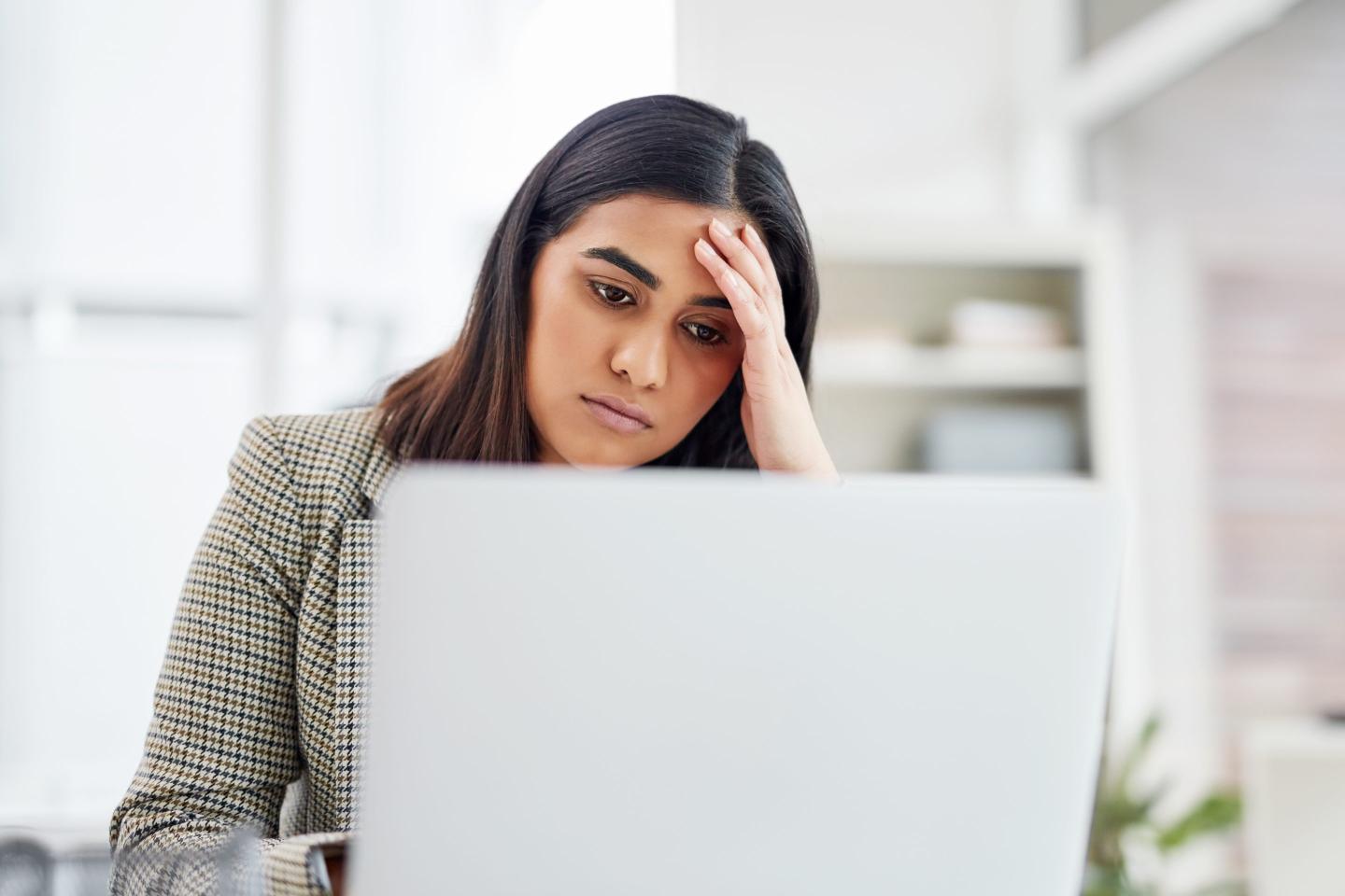 Shot of a young businesswoman looking stressed out while working on a laptop in an office