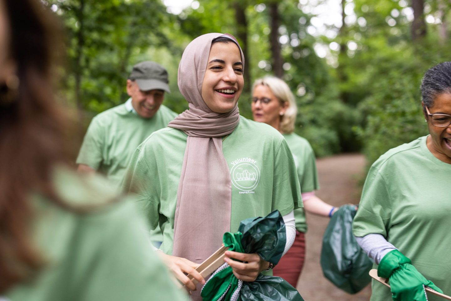 A volunteer smiles as they pick up trash with coworkers.