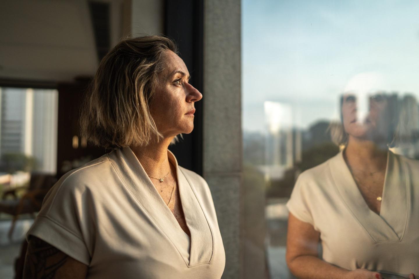 Contemplative woman looking through the window of an office