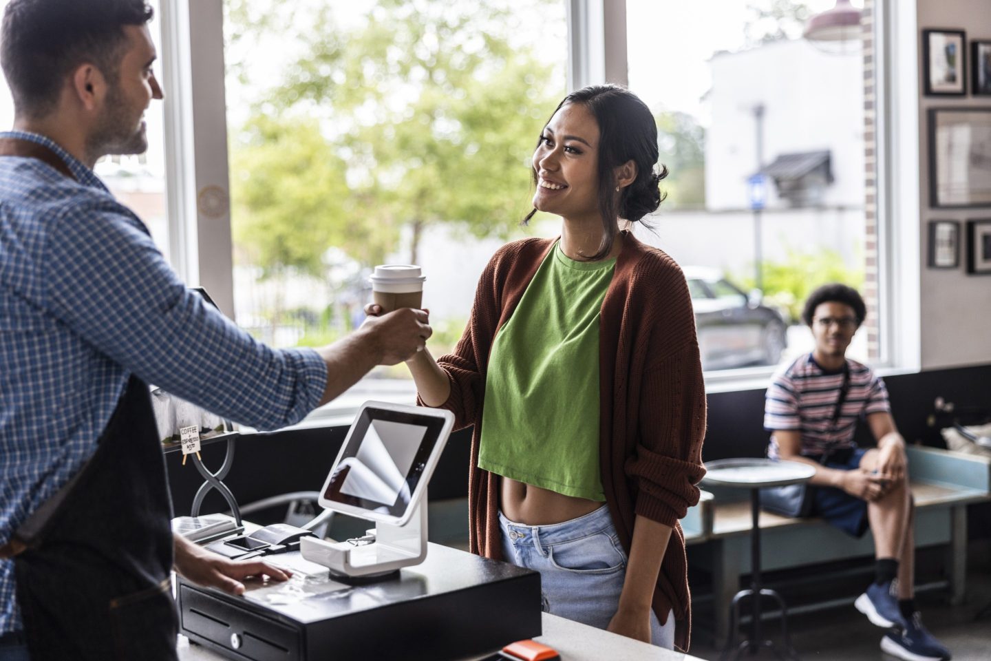 Young woman buying a coffee with contactless electronic payment