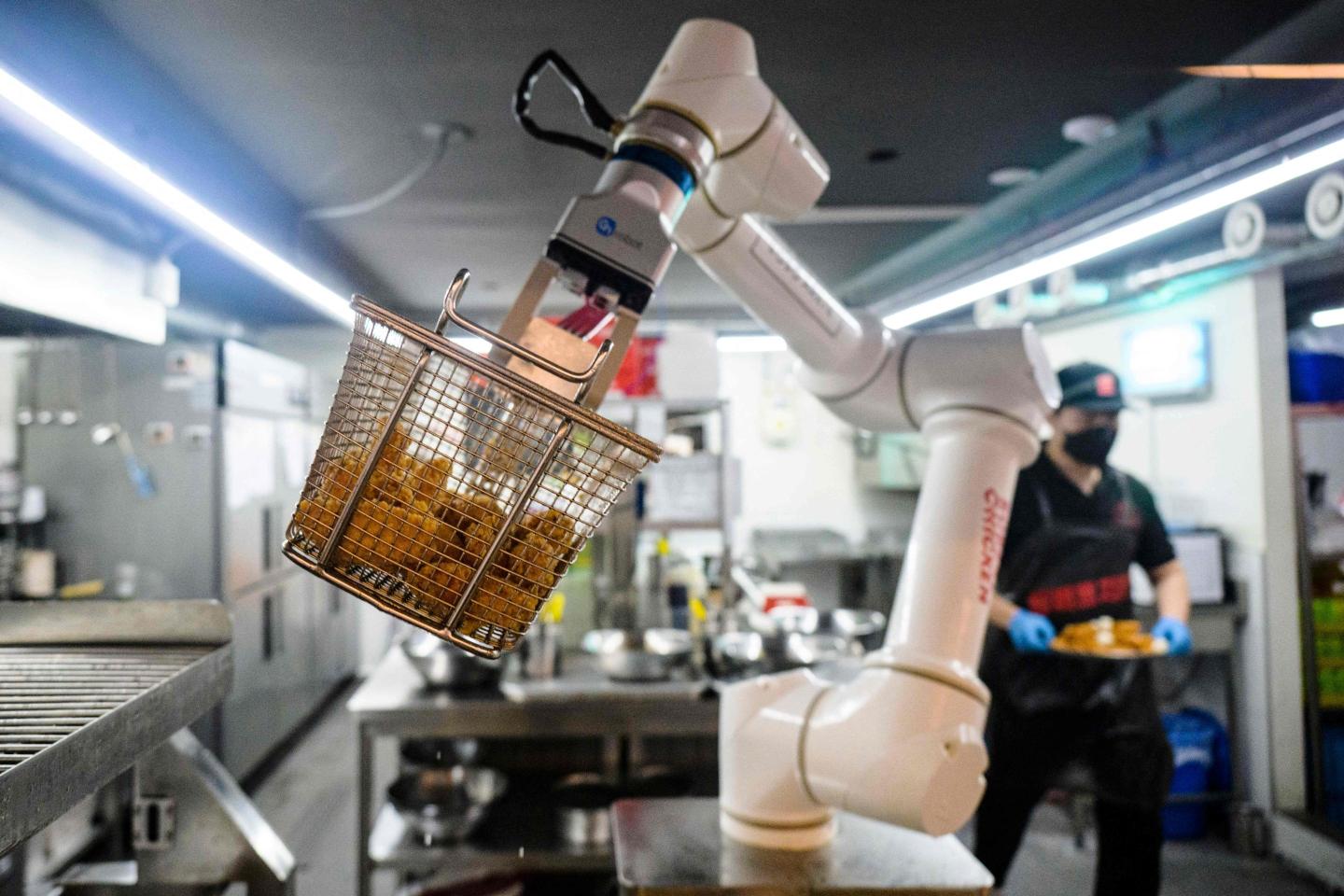 A robot arm has a basket of fried chicken at the end of it