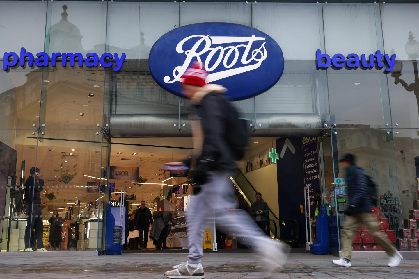 Pedestrians pass a Boots store in London, UK.