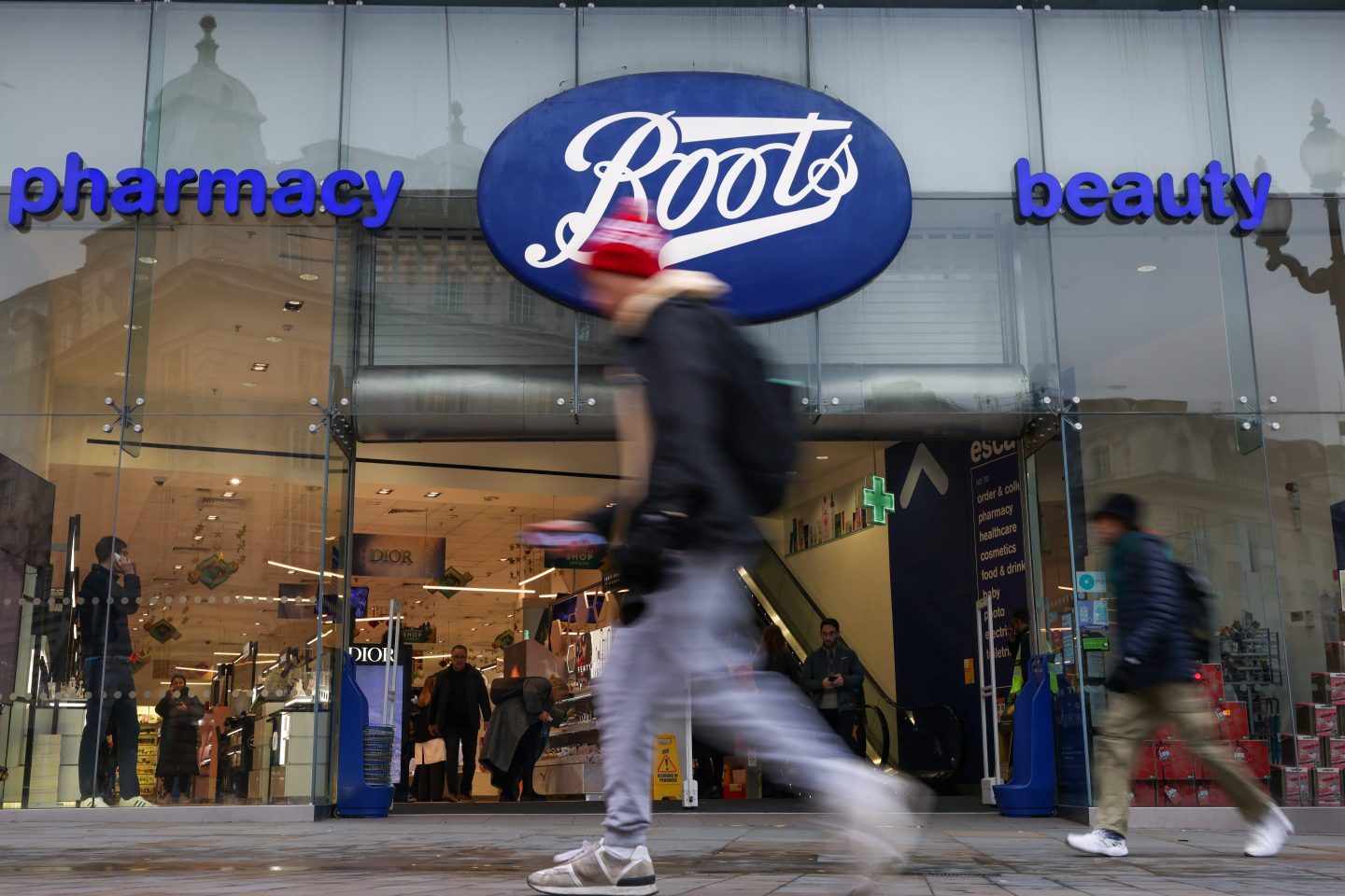 Pedestrians pass a Boots store in London, UK.