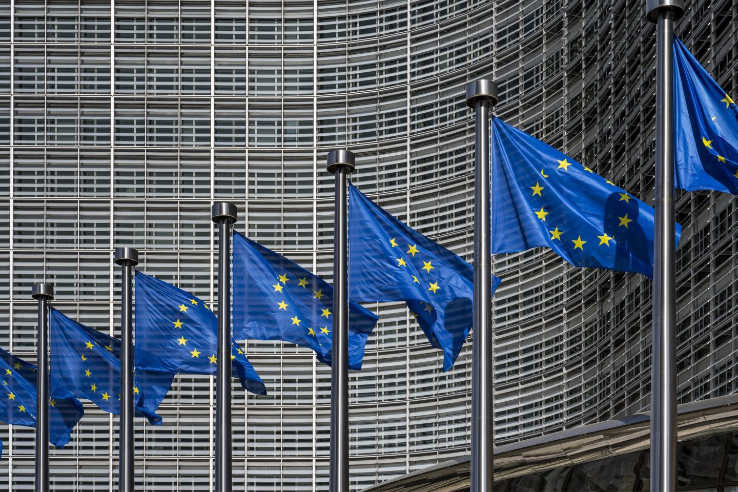 Image of European flags flying in front of the European Commission building.