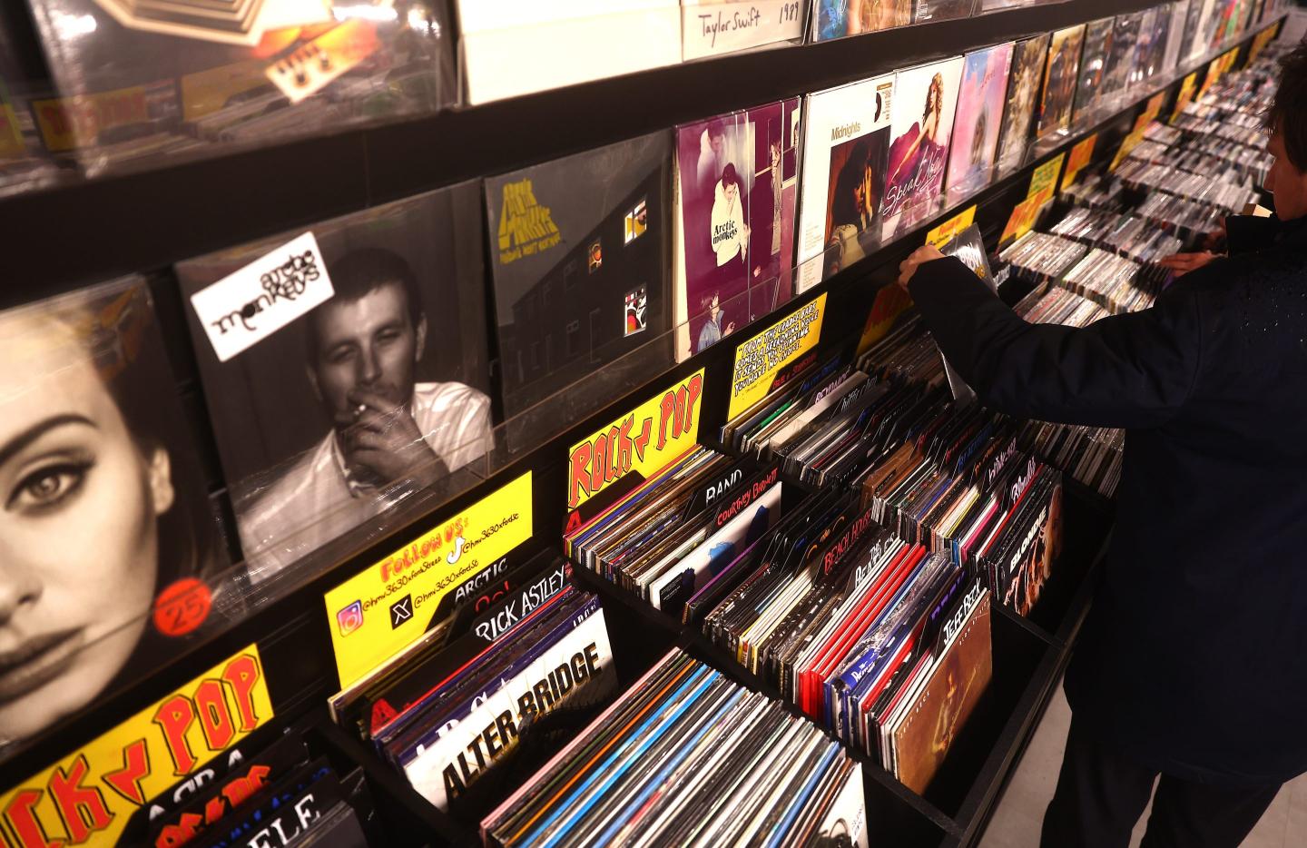 Several rows of vinyl records in a store and a person looking through them