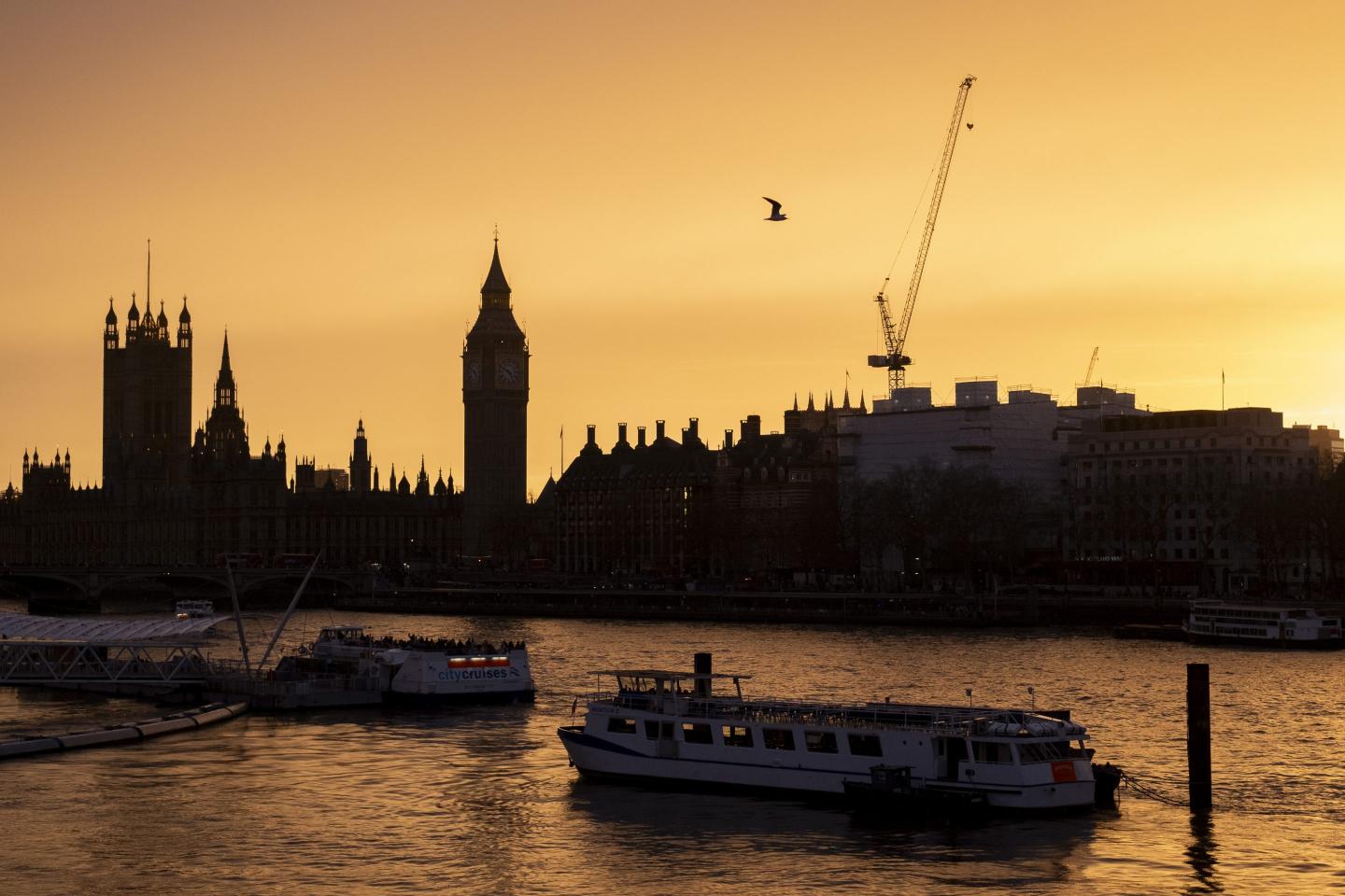 View looking across the River Thames at sunset towards the Houses of Parliament, the Palace of Westminster and clock tower Big Ben.
