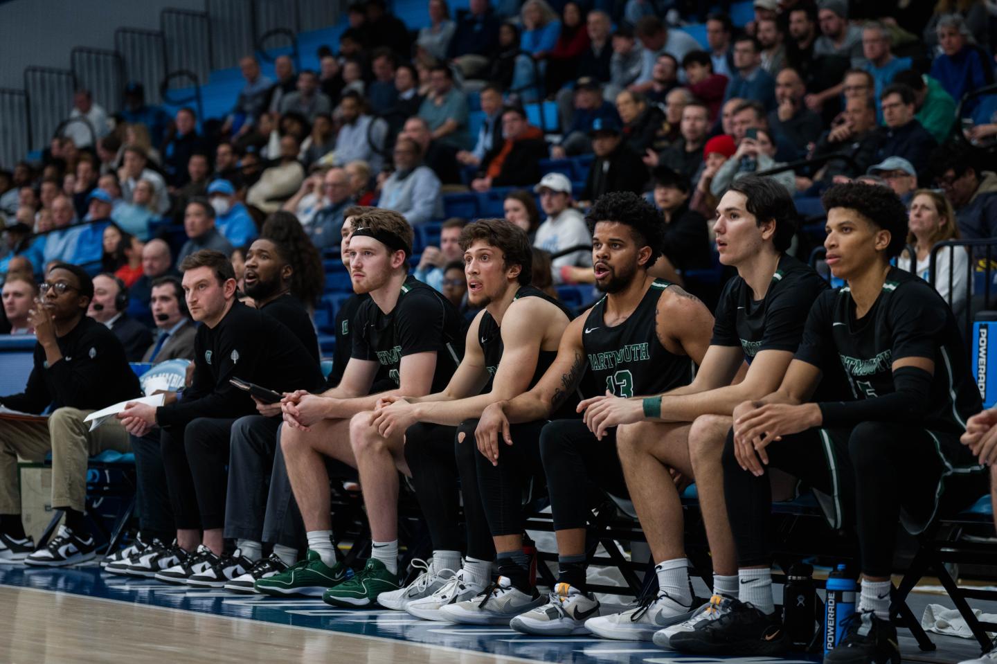 The Dartmouth men's basketball team sitting on a bench.