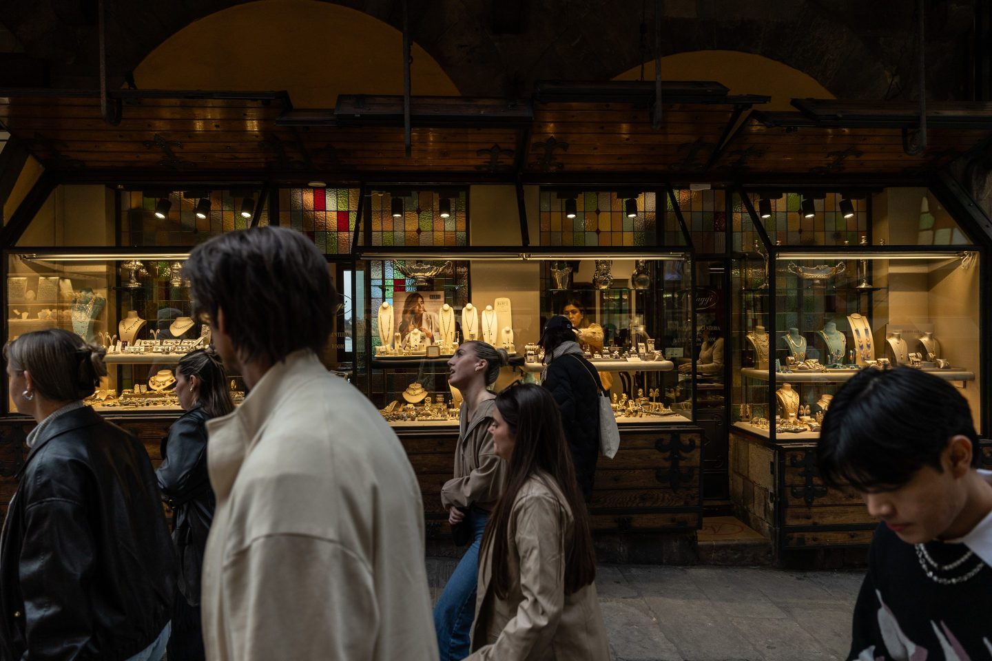 People walk past a jewelry shop located on the Ponte Vecchio medieval arch bridge