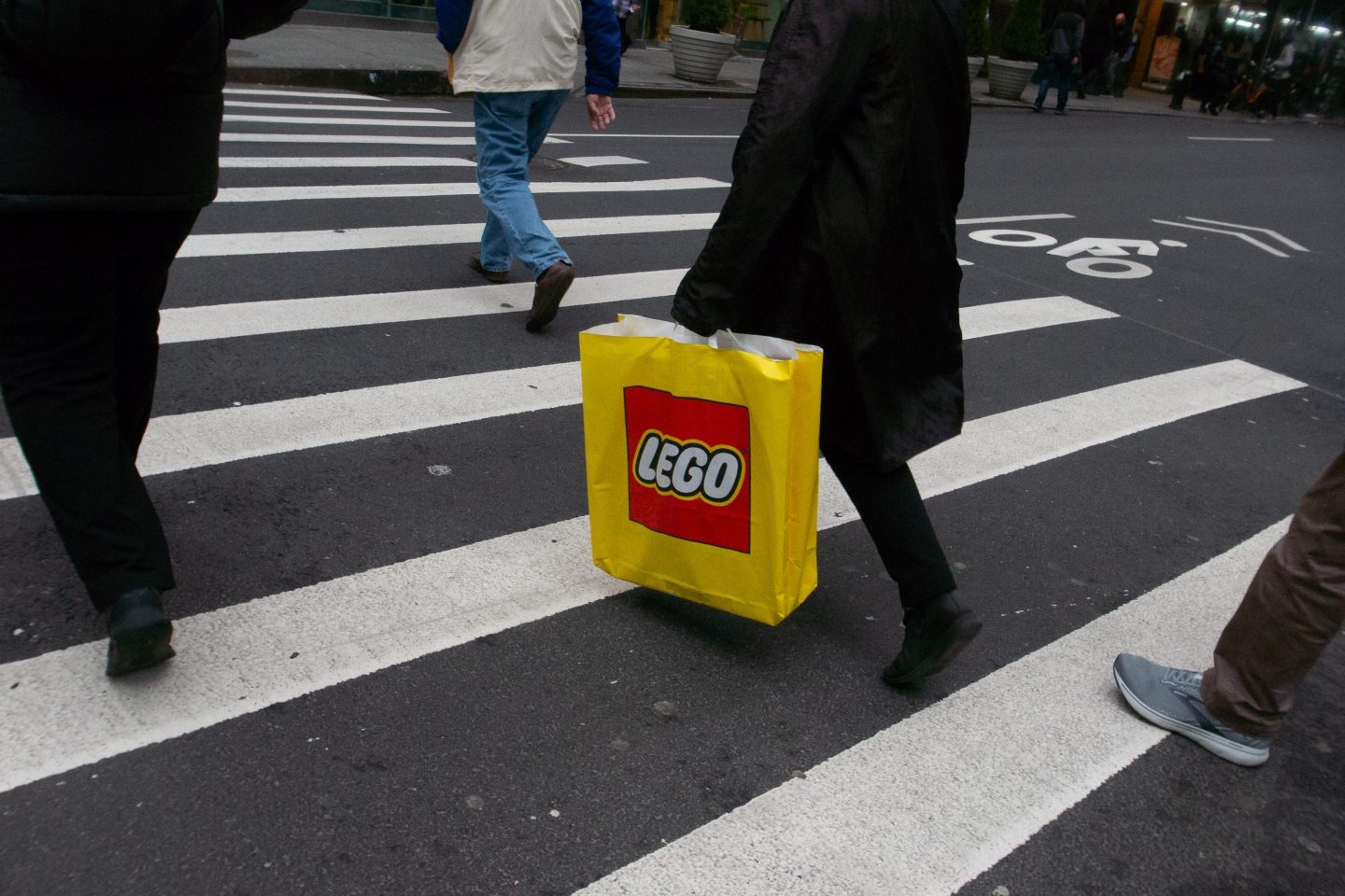 person carrying lego bag in their hand at a crossing