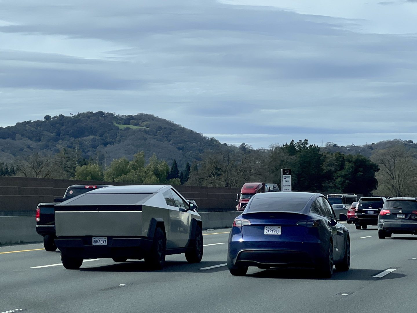 A Tesla Cybertruck is seen driving beside a Tesla sedan