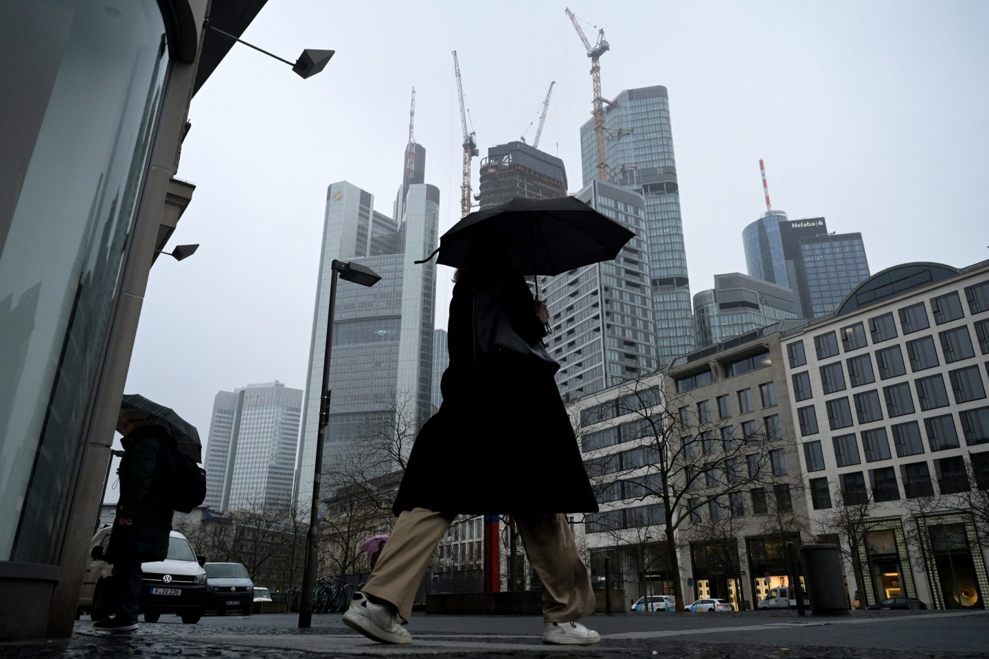 A woman uses an umbrella to shelter from the rain as she walks past the banking district in Frankfurt, Germany.