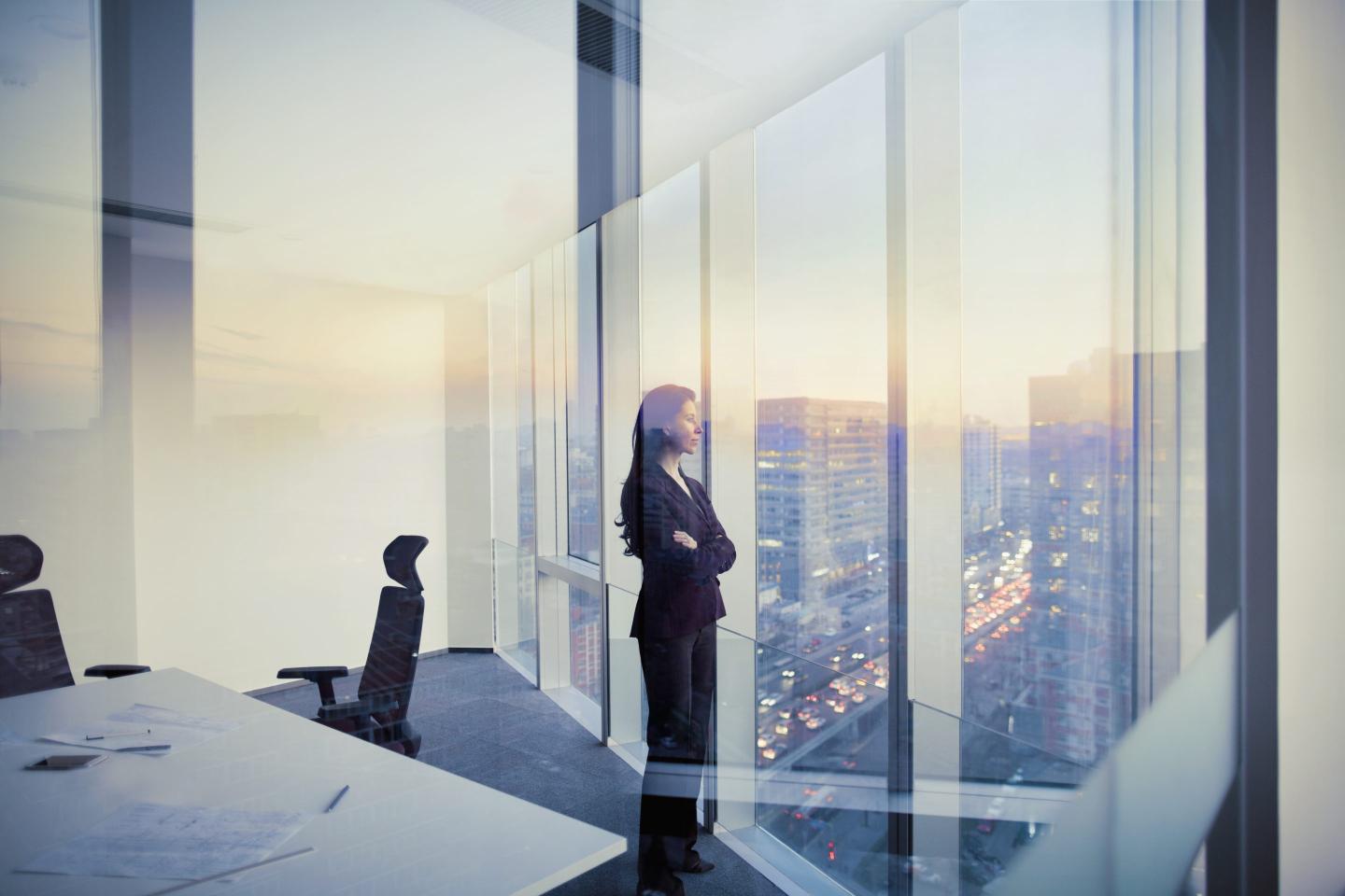 An image of a woman standing alone in a boardroom.