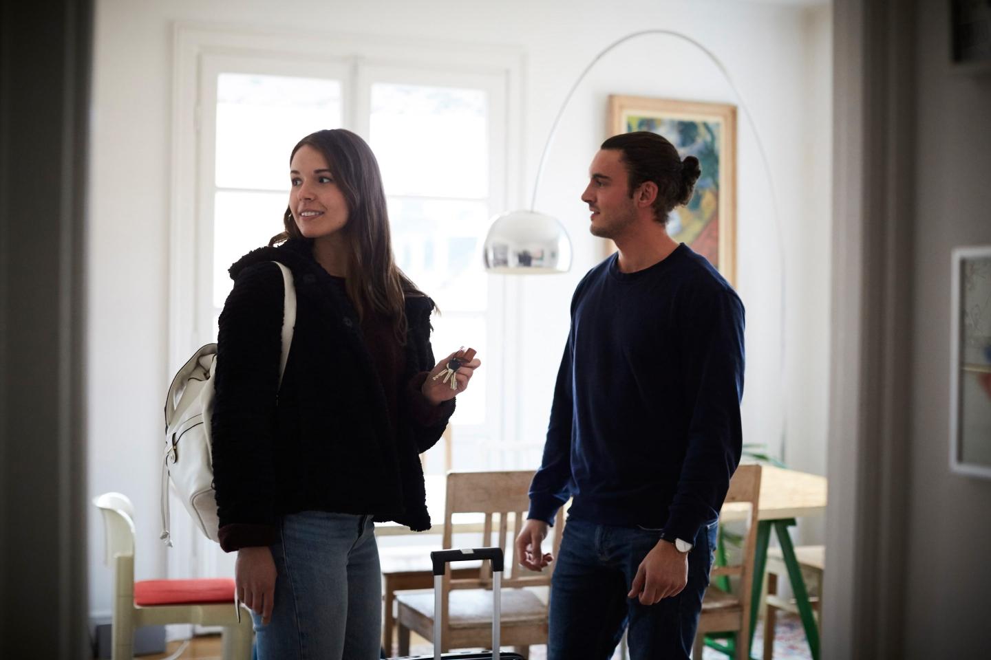 Smiling man and woman standing in apartment on sunny day