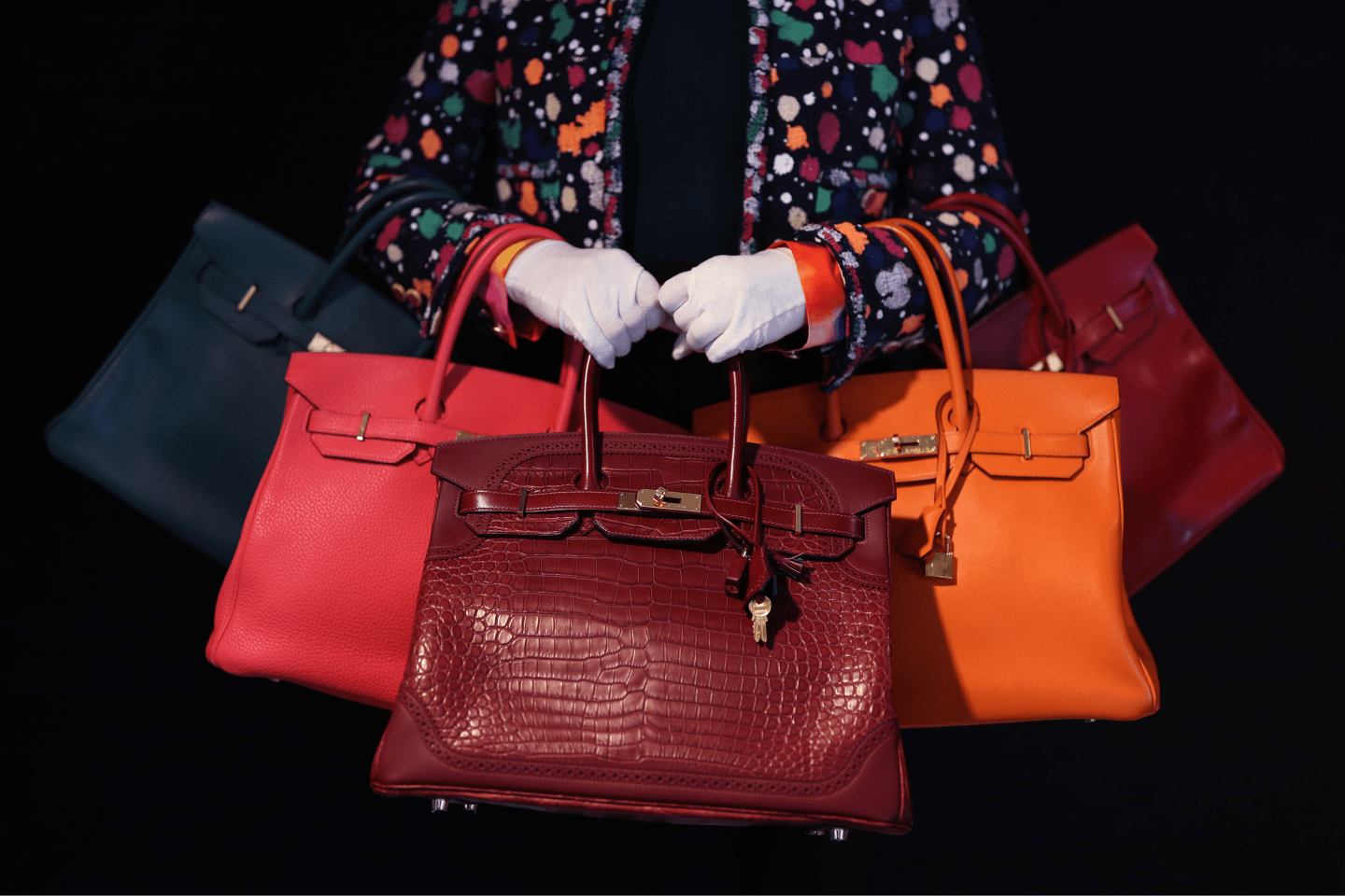 Meg Randell, Head of Designer Handbags and Fashion at Bonhams, holding a range of 'Birkin' bags, including (centre) a matte bourgogne Porosus crocodile and rouge H Ghillies Birkin 35, Hermes, Limited Edition c. 2015, £ 40,000 - 50,000, during a preview of Bonhams' designer handbags and fashion sale, Bonhams, London.