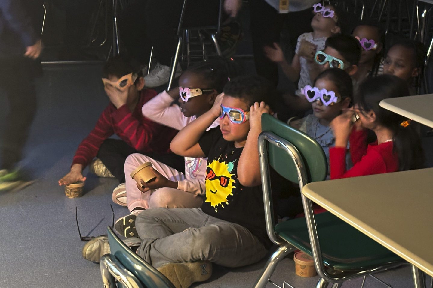 Second-grade student Jose Byrd (black t-shirt with sun) and classmates try out eclipse viewing glasses that they decorated at Riverside Elementary School in Cleveland on March 14.