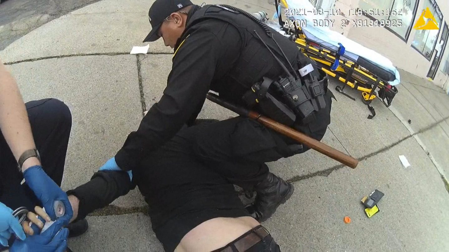 Police restrain a man on the sidewalk