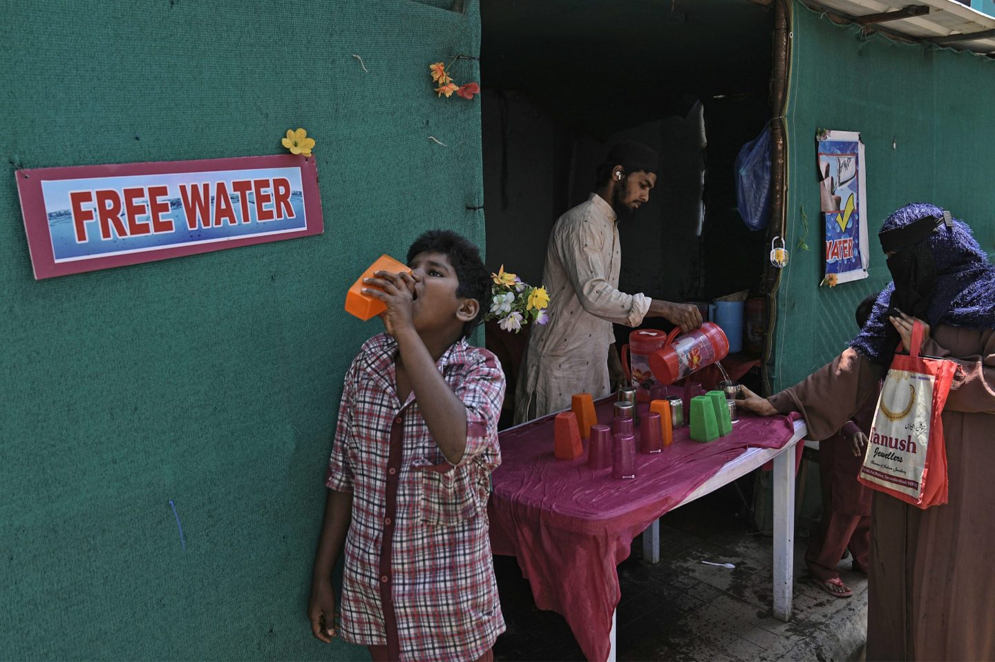 A volunteer distributes drinking water next to a bus stand on a hot summer day in Hyderabad, India, on March 21, 2024.