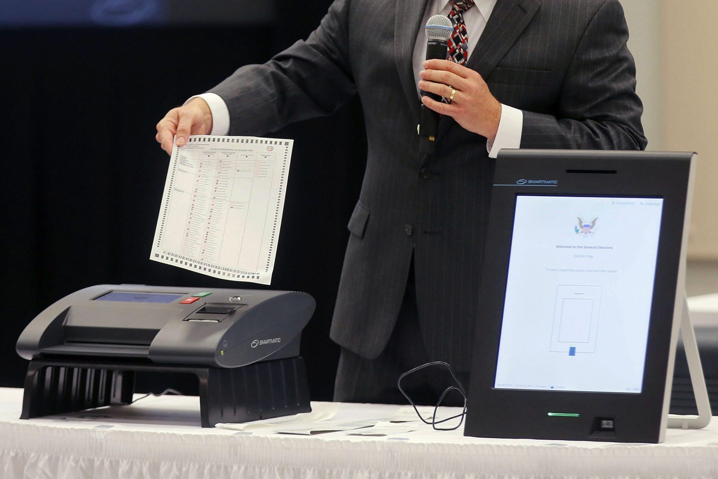 A Smartmatic representative demonstrates his company's system, which has scanners and touch screens with printout options, at a meeting of the Secure, Accessible & Fair Elections Commission, Aug. 30, 2018, in Grovetown, Ga.