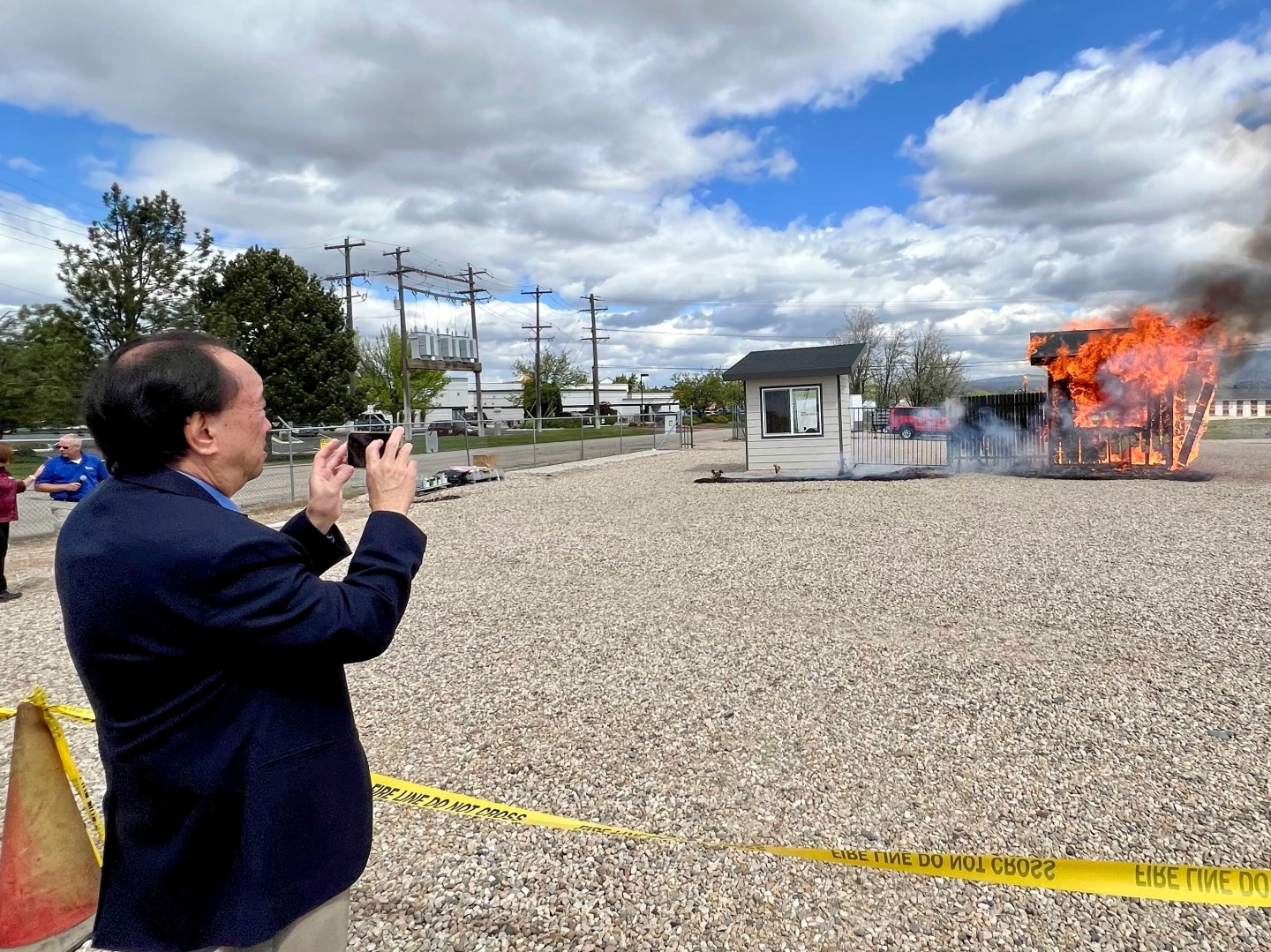 Hawaii Insurance Commissioner Gordon Ito films a wildfire burn risk demonstration at the National Interagency Fire Center in Boise, Idaho, on April 29, 2024.