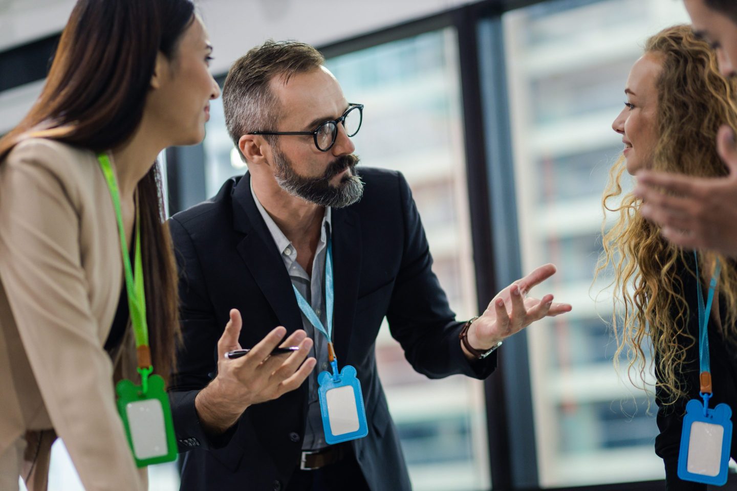 A business man speaks and motions to two other business people at a networking event.