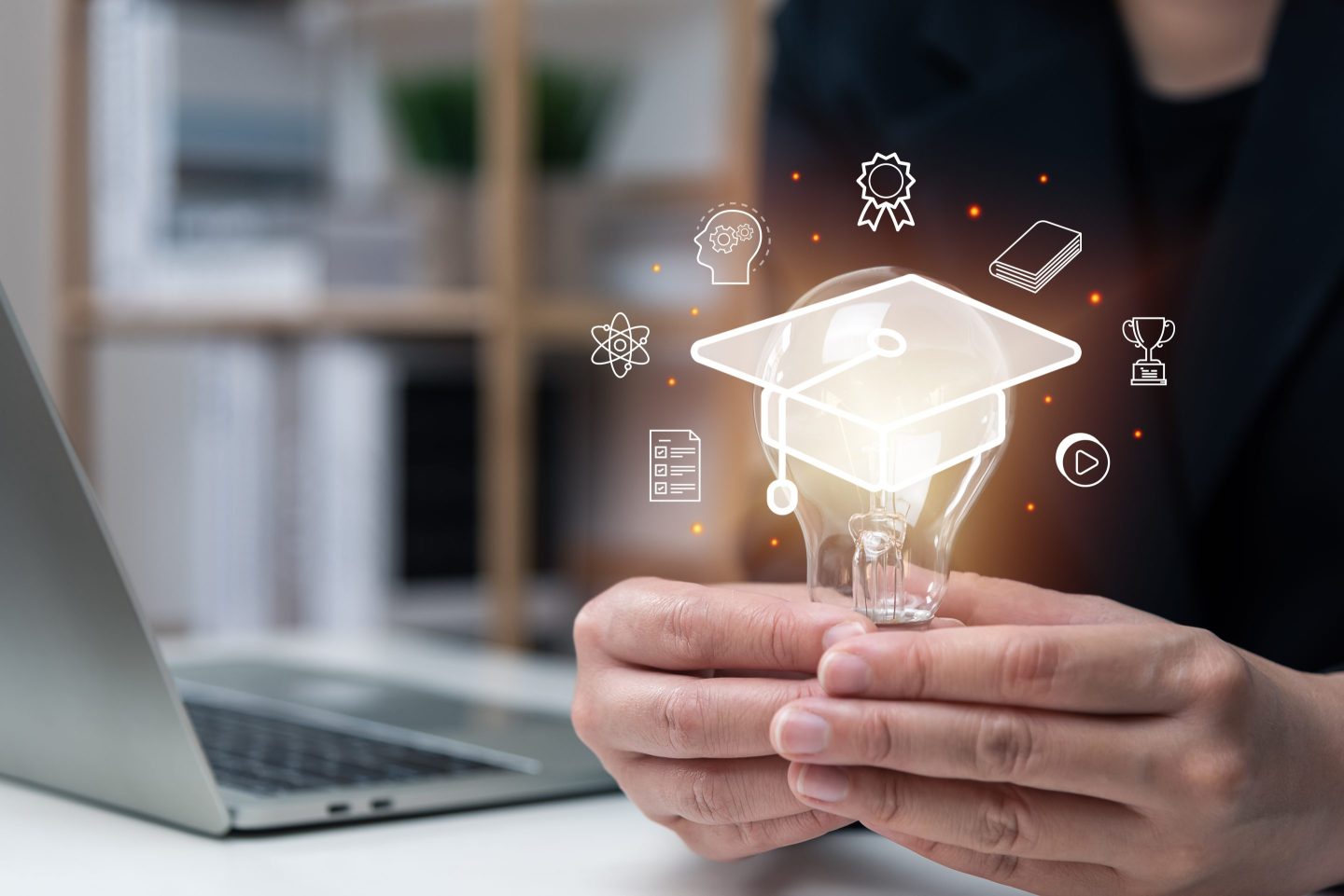 Businessman hand holding light bulb with graduation gap and other education items highlighted around it