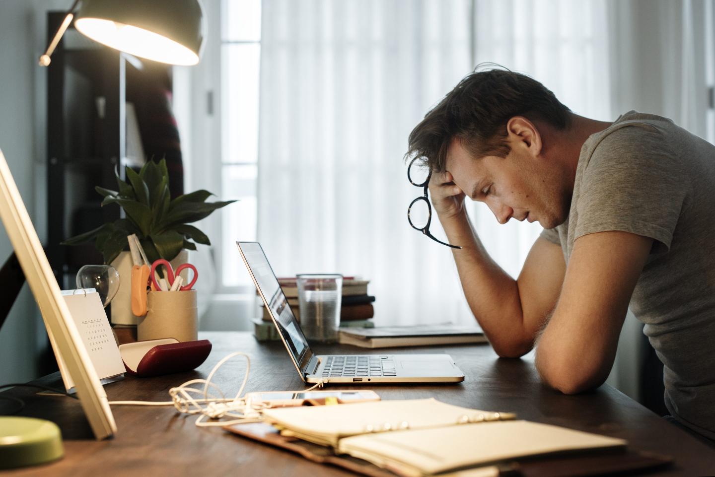 Remote worker is stressed at his laptop.