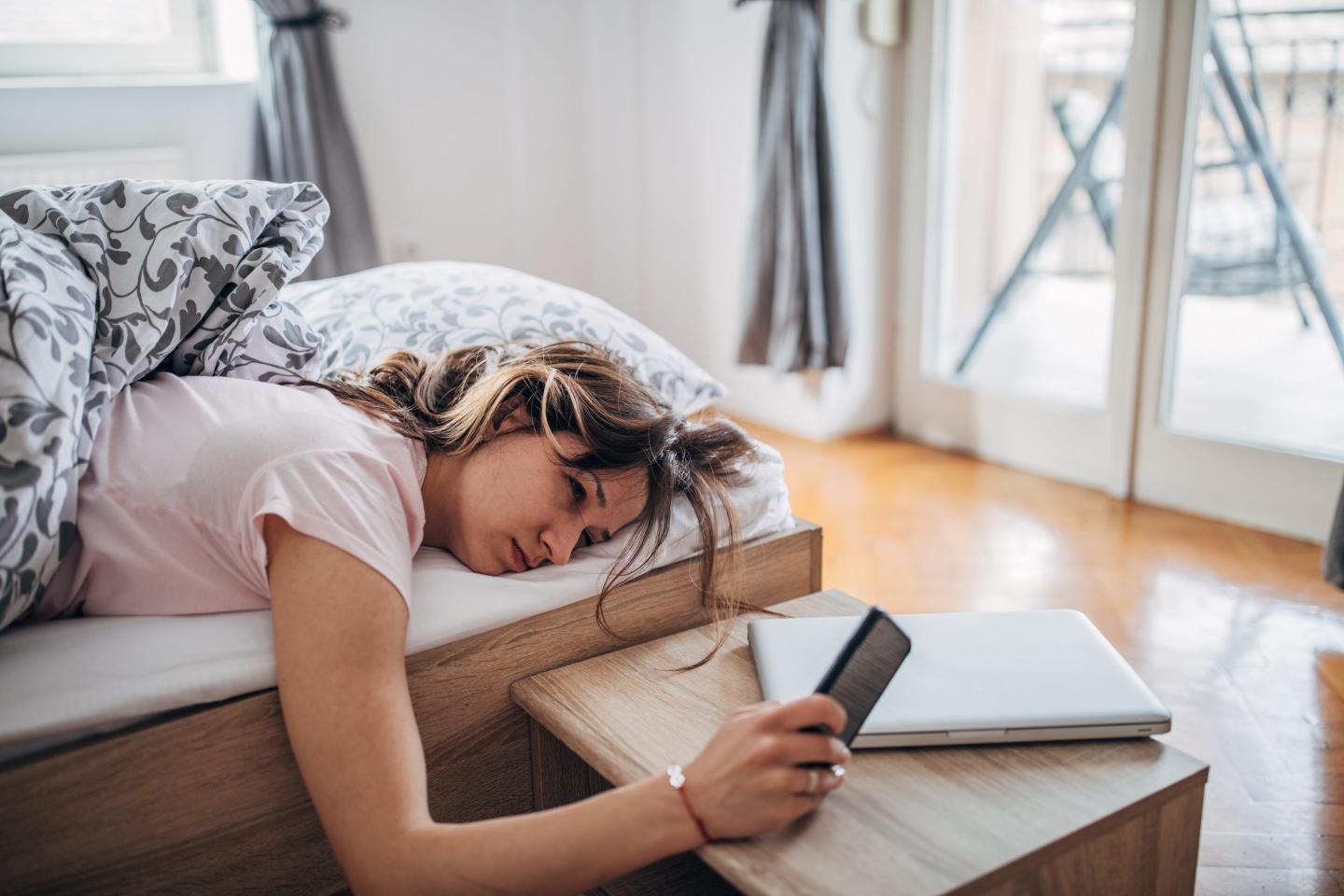 Young person on their phone in bed