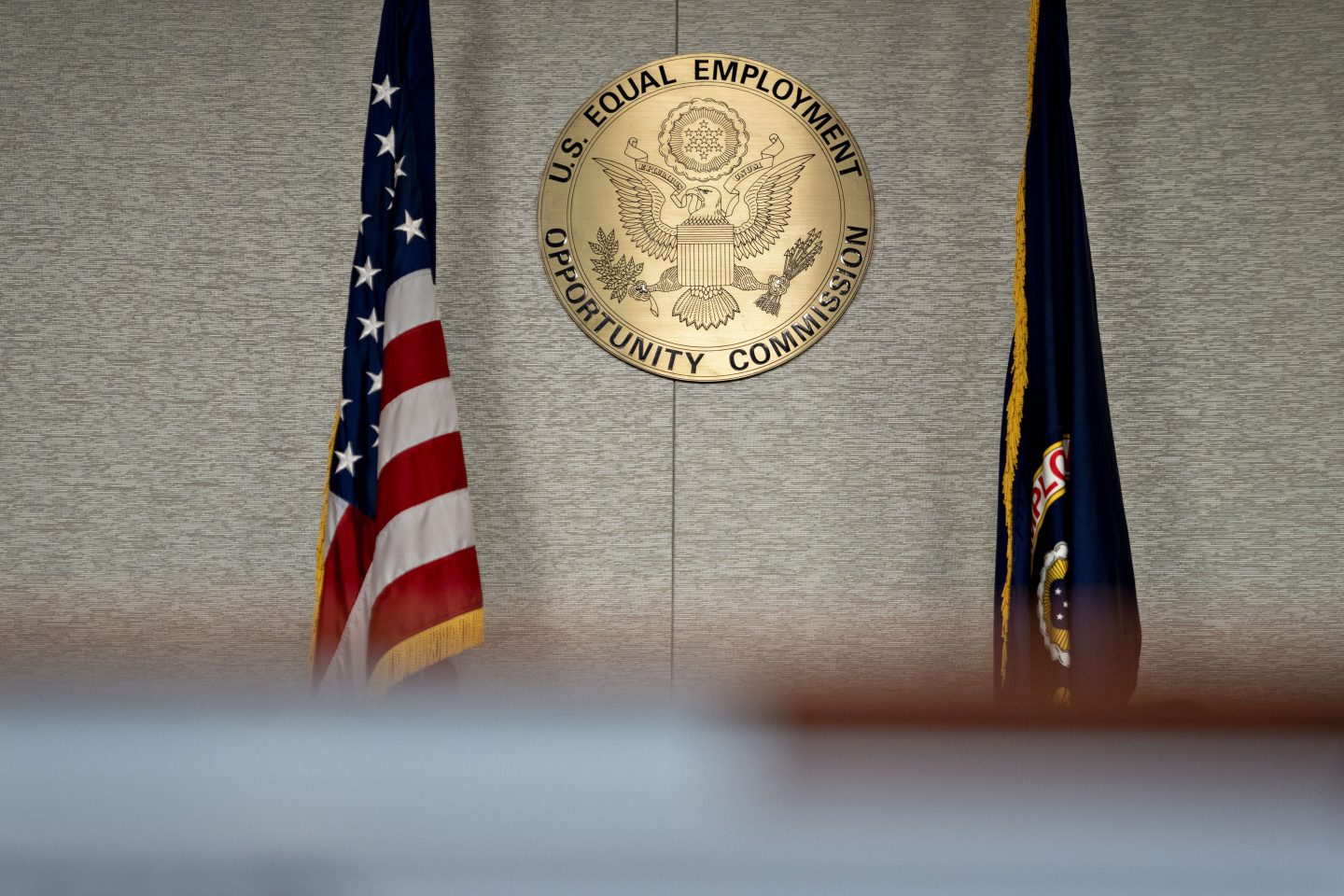 The Equal Employment Opportunity Commission (EEOC) seal hangs inside a hearing room