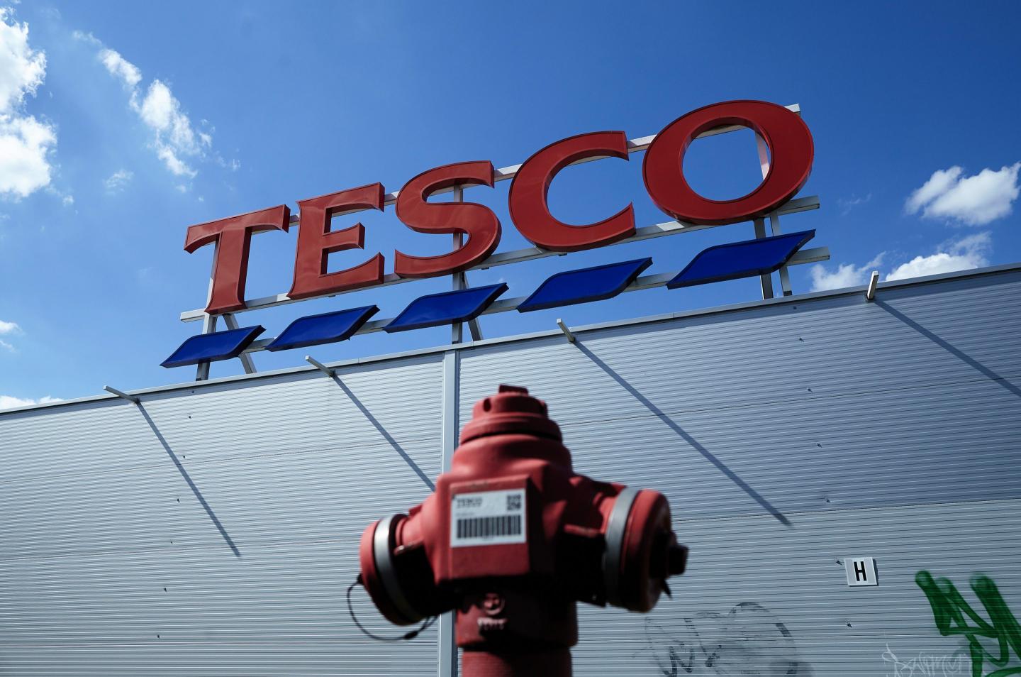 A logo sits on display above a Tesco Plc supermarket