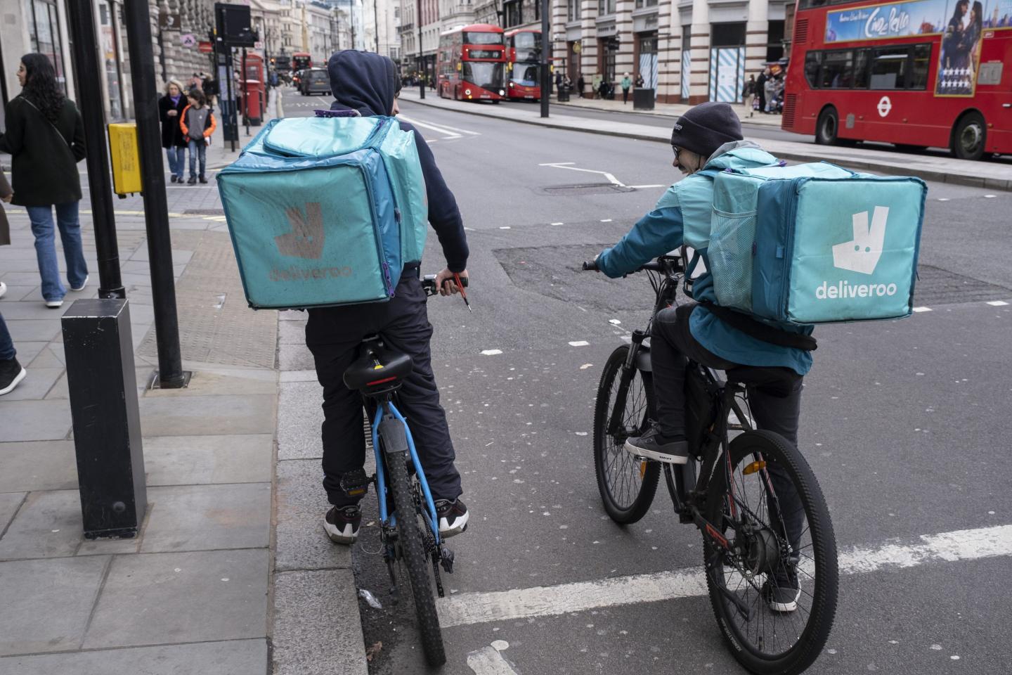 Deliveroo food delivery riders / cycle couriers waiting at traffic lights on 17th February 2022 in London, United Kingdom.