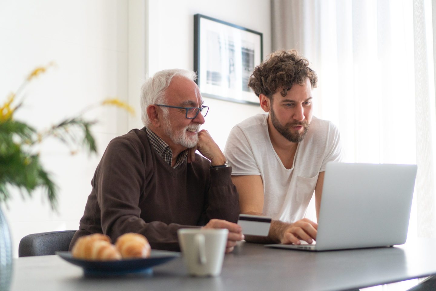 Grown son and senior dad using laptop