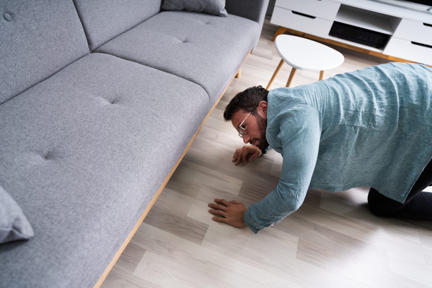 Man looking underneath couch