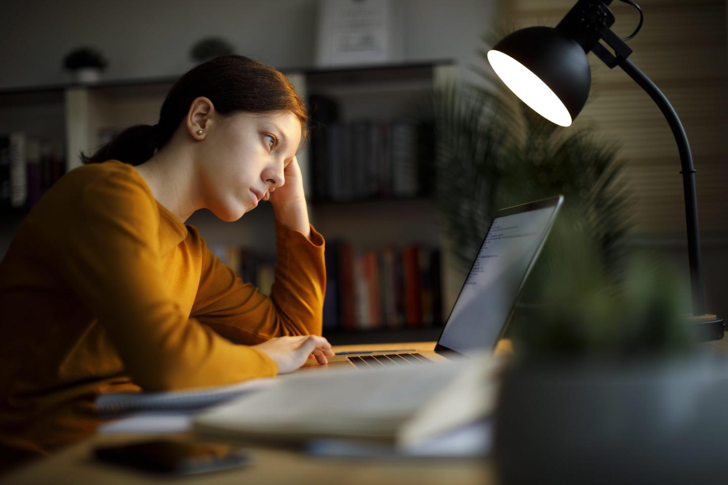 Worried teenage girl studying late at night