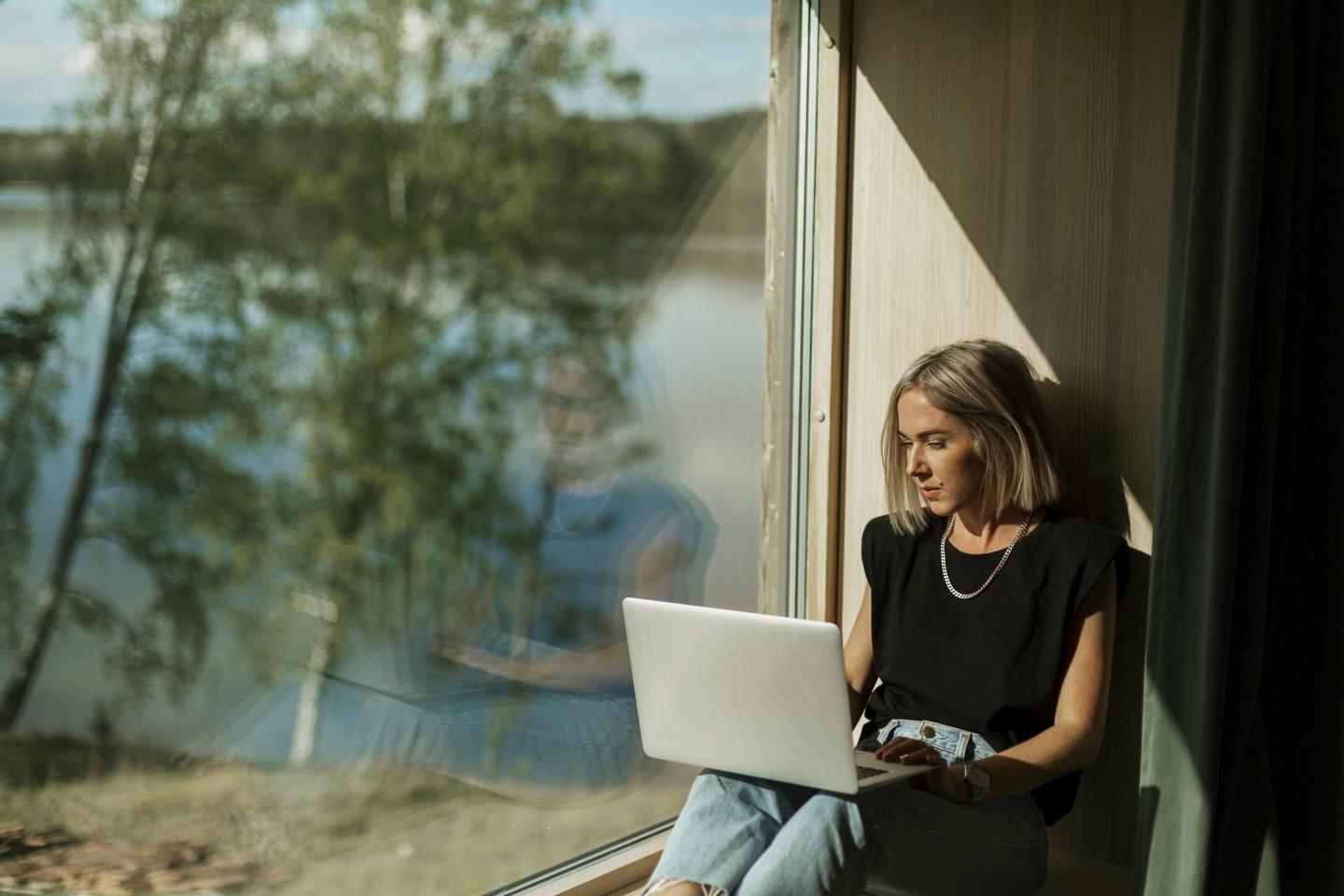 Woman using laptop near window