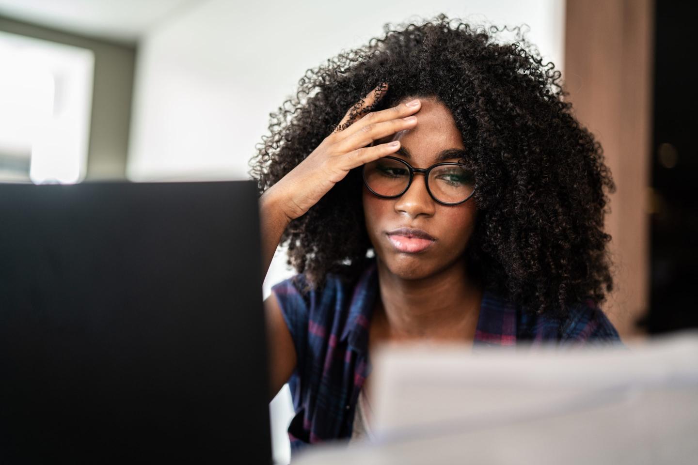 Tired looking woman at. computer looks at resumes