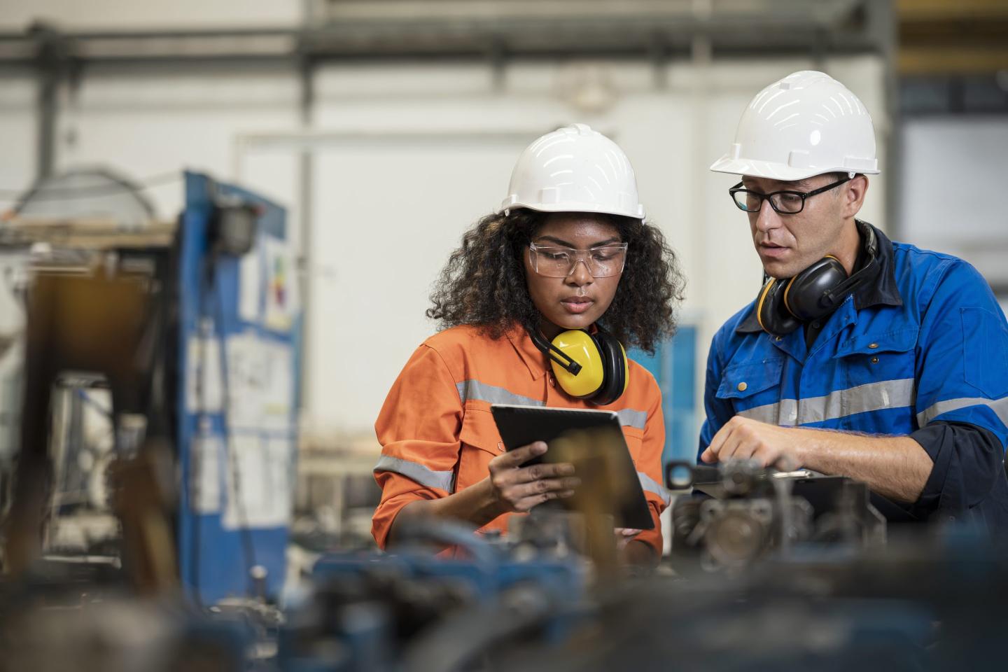 Two manufacturing employees discuss fixing an issue.