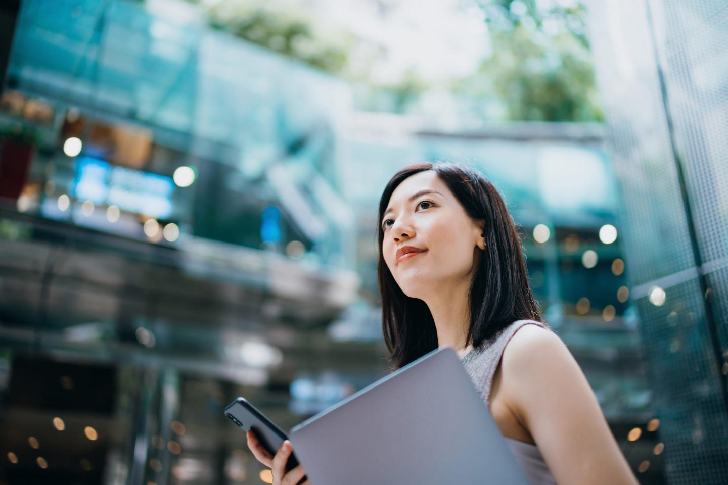 Young Asian businesswoman carrying smartphone and laptop