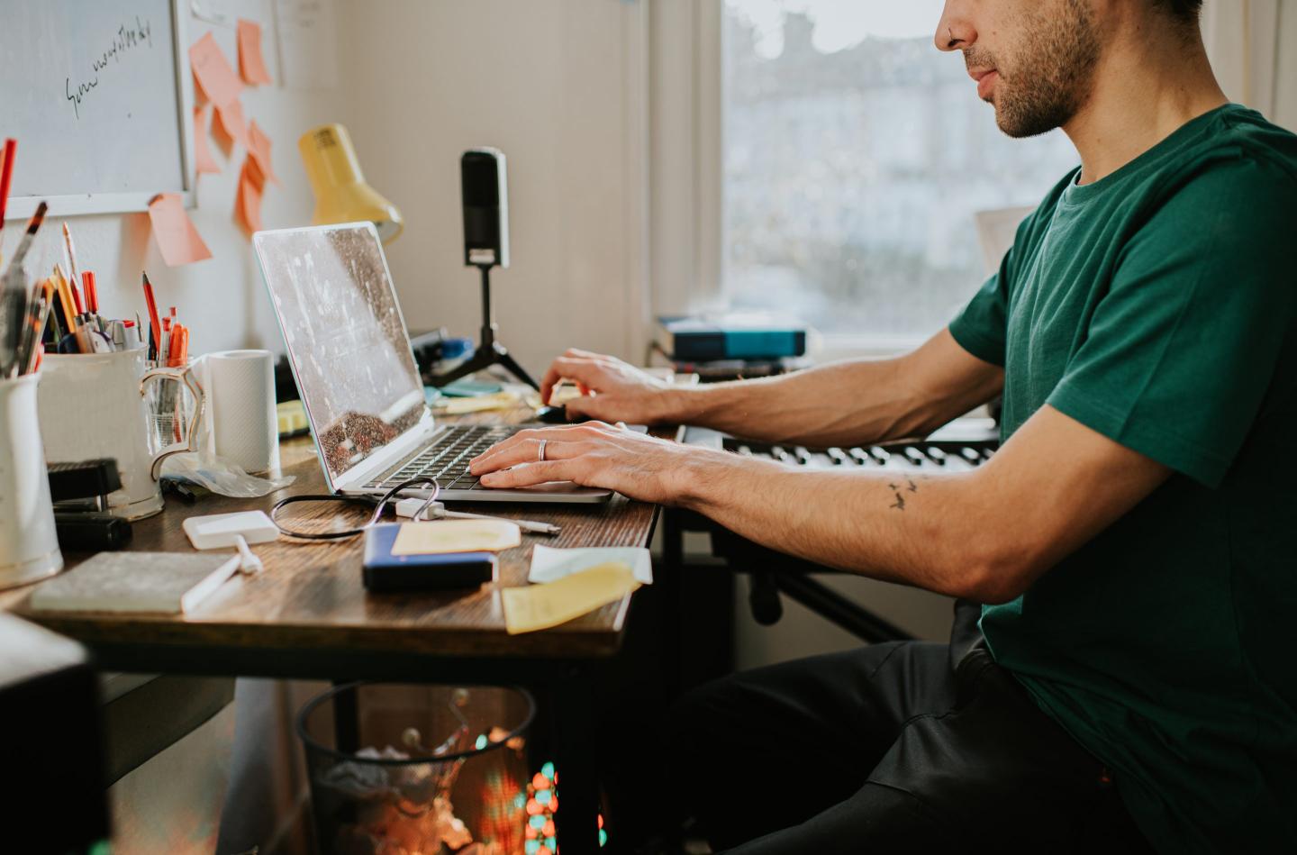 person sitting on a work desk with laptop and stationery