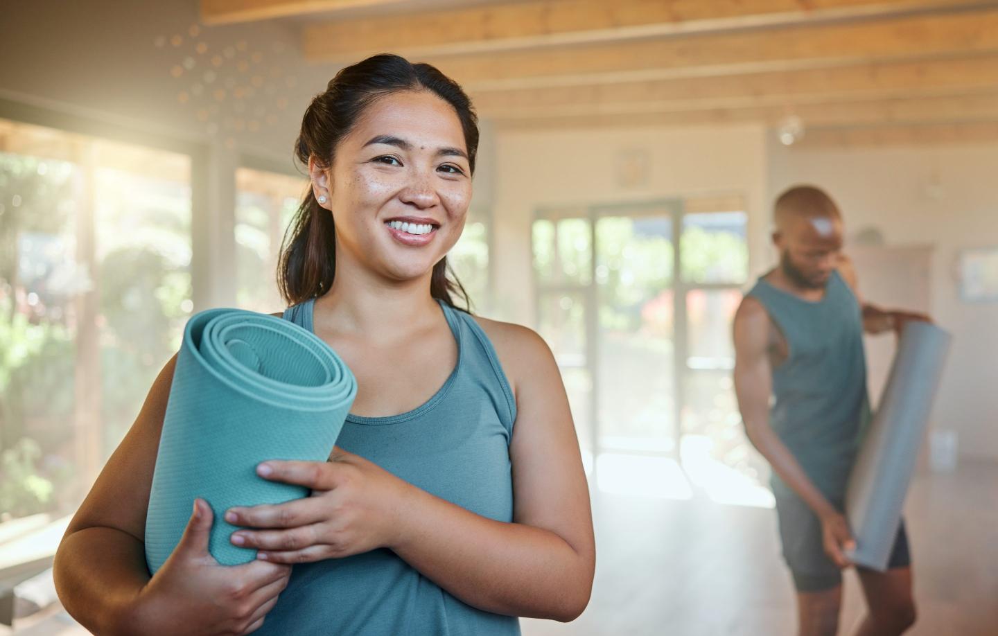 Ready, fitness and portrait of a woman at yoga, exercise or training with people at the gym. Health, sports and girl with a mat and smile to start pilates, cardio wellness or a workout at a gym