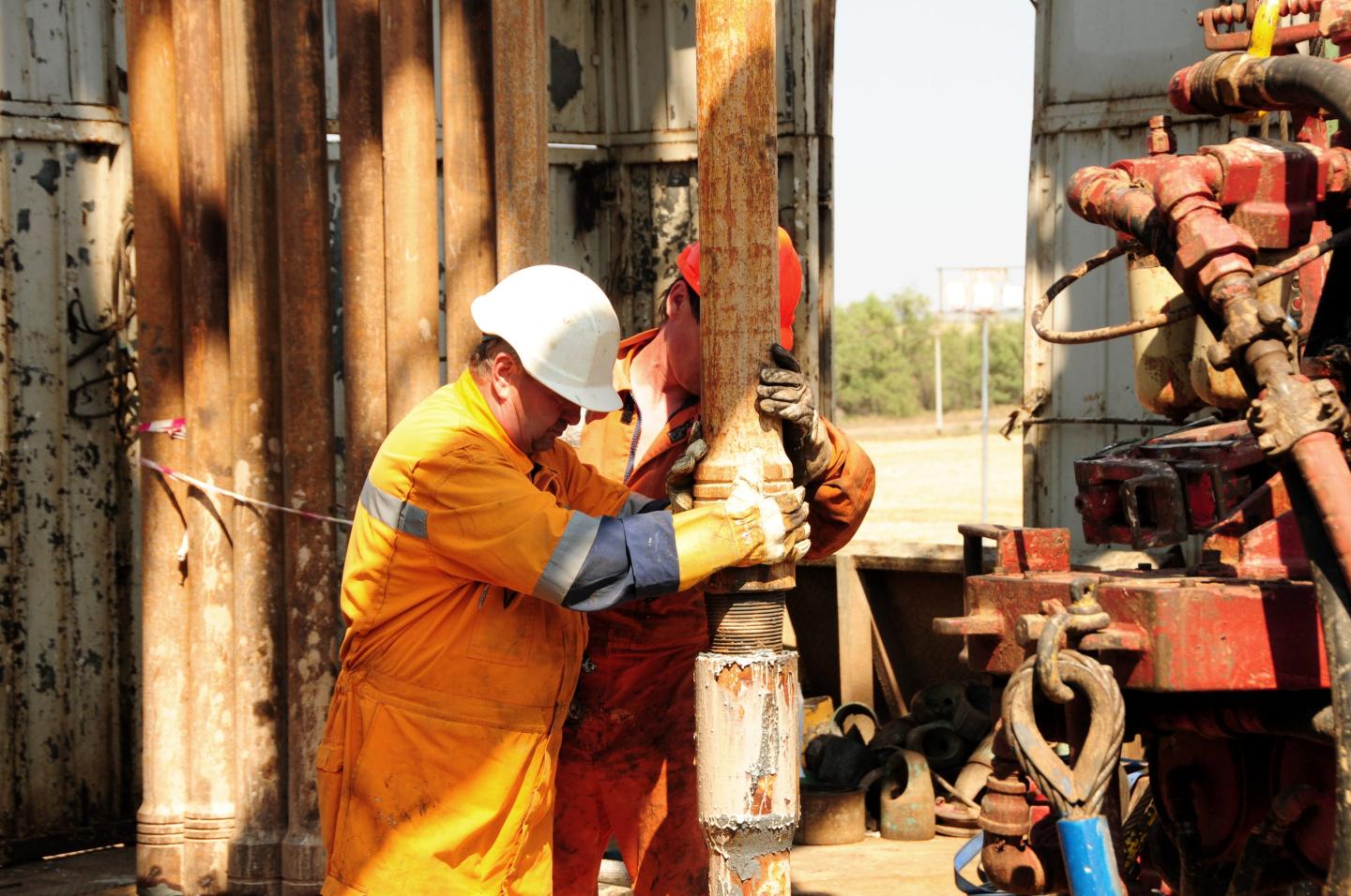 workers on an oil rig position a drill