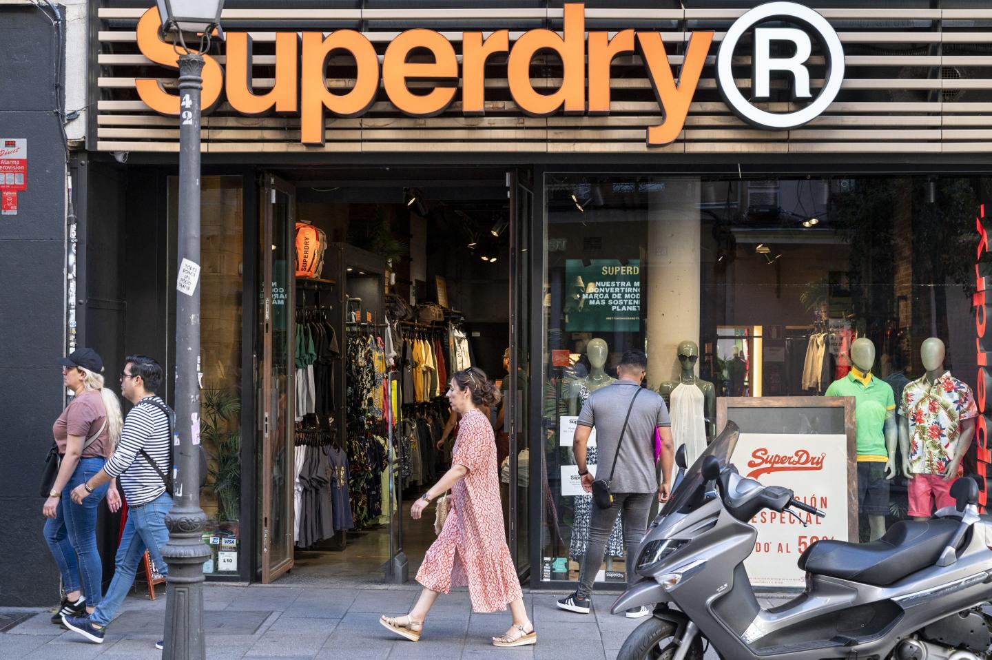 people walking on a busy street outside a superdry store