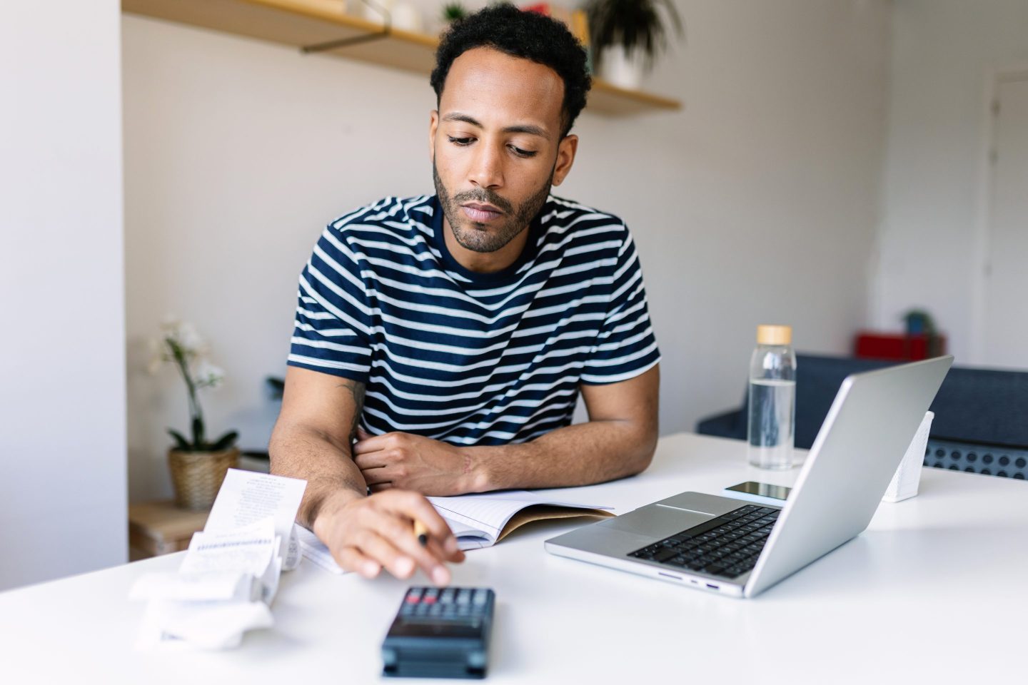 Man doing taxes with a calculator and computer