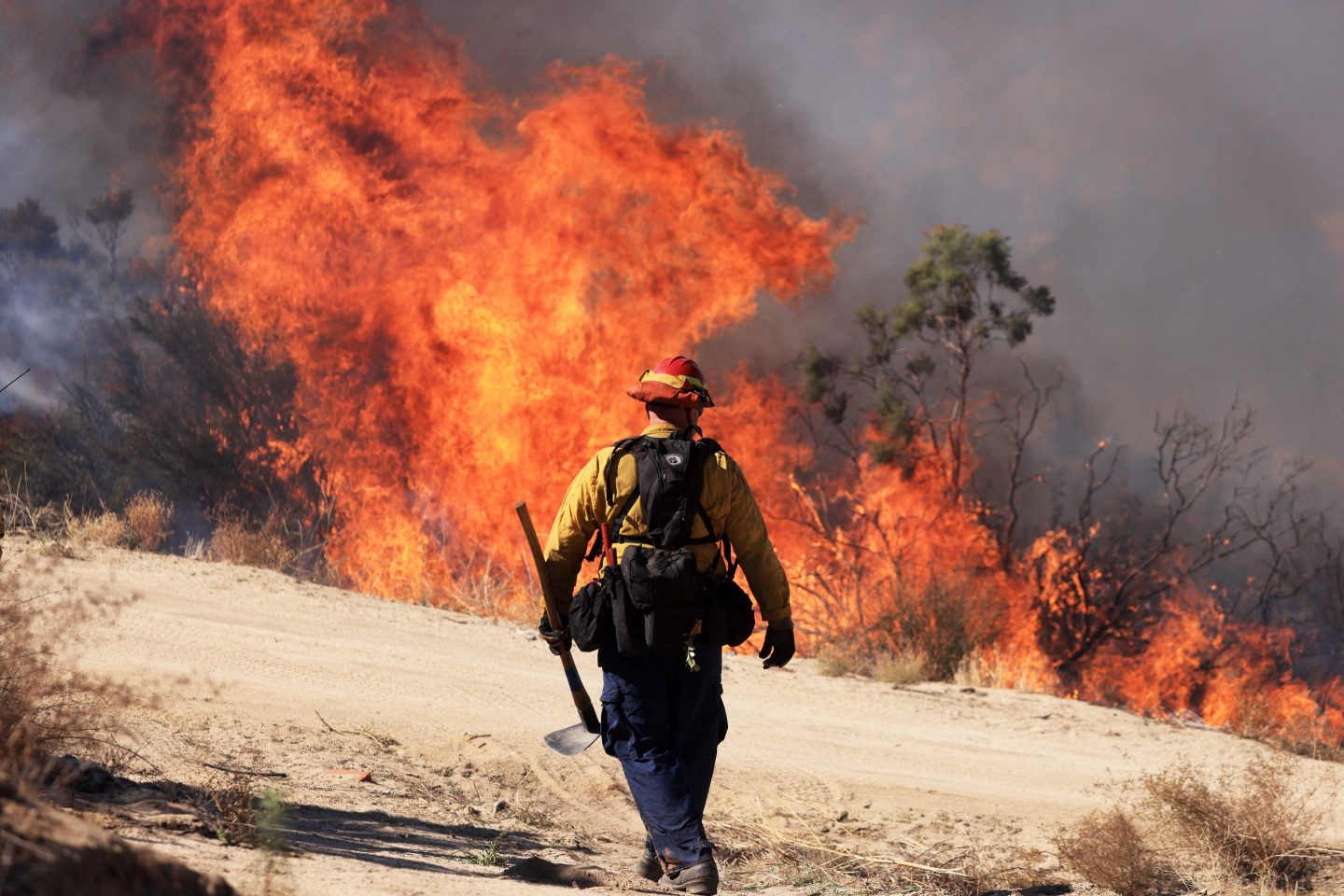 A firefighter walks toward flames as the Highland Fire burns in Aguana, California