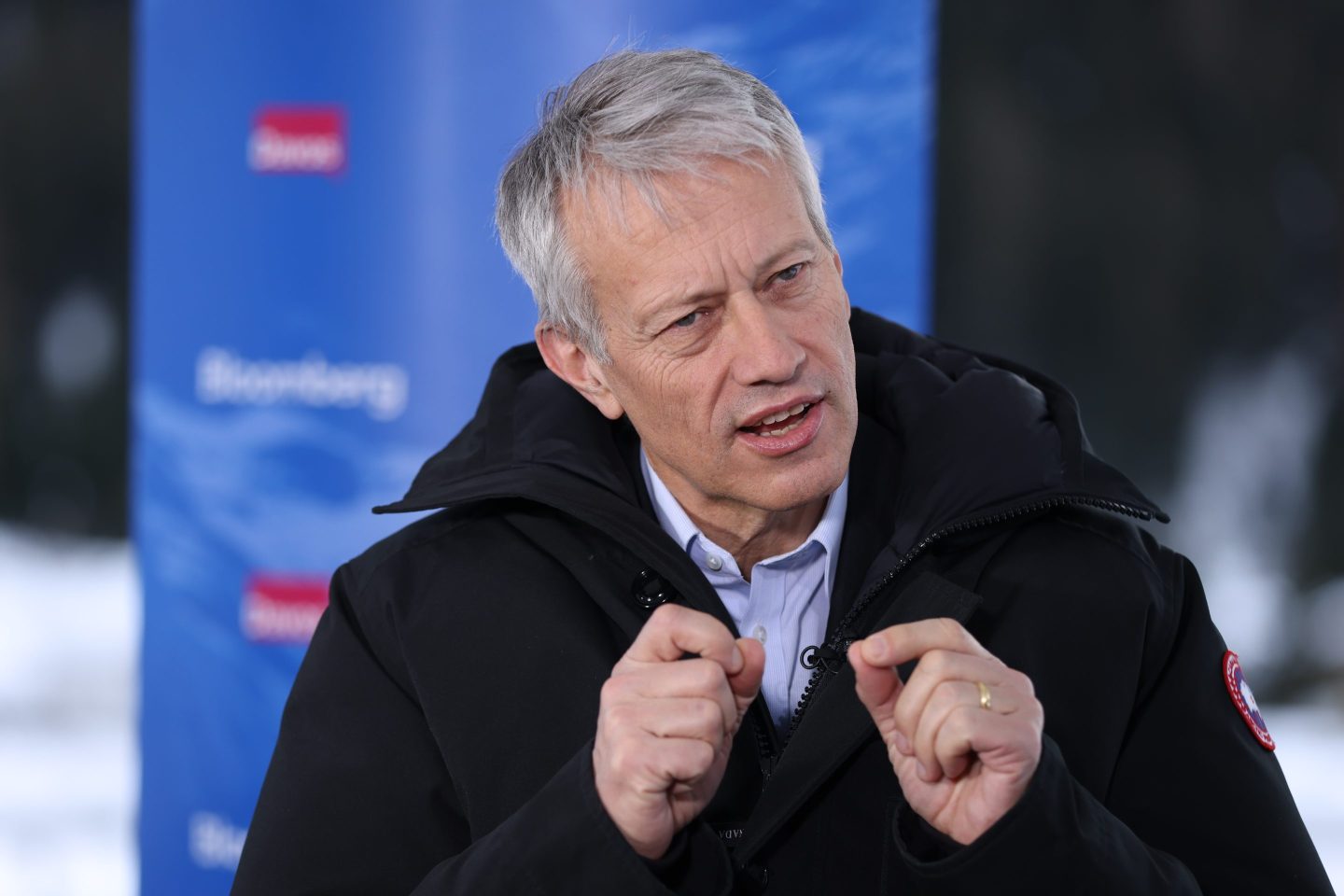 James Quincey is wearing a black coat over a dress shirt and gesturing as he speaks.