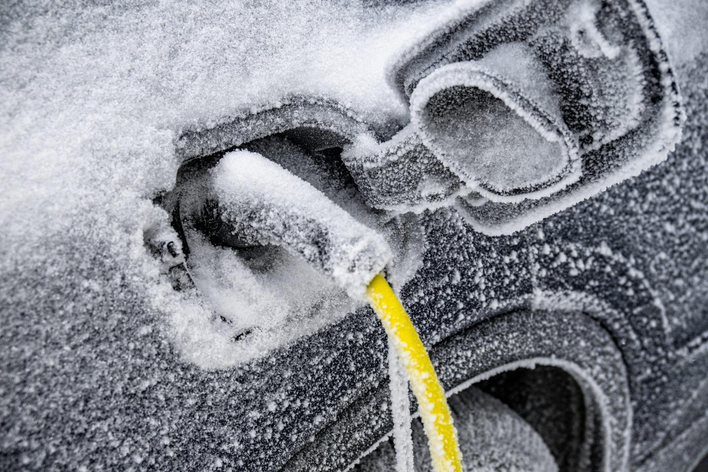 The electric car needs charging and is covered with ice